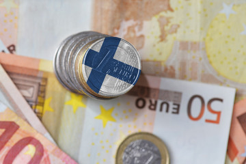 euro coin with national flag of finland on the euro money banknotes background.