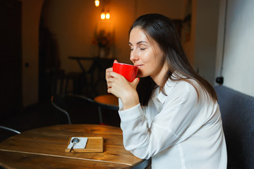 Wall Mural - Red cup of coffee in the hands of a beautiful smiling girl