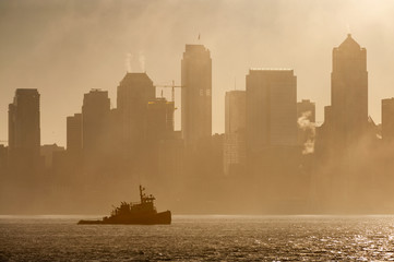 Wall Mural - Tug Boat on Elliott Bay on a Foggy Morning. The Seattle skyline is silhouetted as a tugboat works the waters of Elliott Bay during a glorious foggy sunrise.