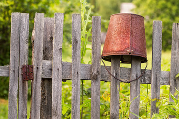 Old rusty bucket on a wooden fence