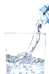 Pouring drinking water from bottle into glass on white background.