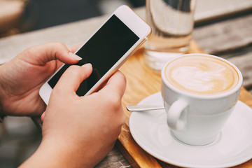 Wall Mural - woman using a mobile phone near a cappuccino cup