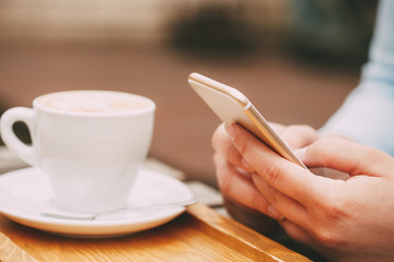 Wall Mural - woman using a mobile phone near a cappuccino cup