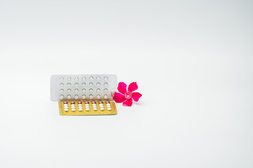 Wall Mural - Contraceptive pills with pink flower on white background