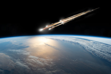 Wall Mural - a meteor streaks towards a collision with earth as it breaks up over the ocean. clouds cover an ocea