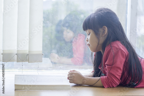 Little Asia Girl Laying Down On Desk And Reading Book Buy This