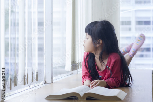 Little Asia Girl Laying Down On Desk And Looking Out Of Winndow