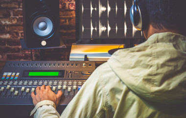 Wall Mural - back of asian sound engineer working in digital sound editing studio, DJ working in broadcasting studio, focus on hands