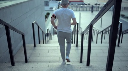 Wall Mural - Dolly move of a sporty man running on the staircases