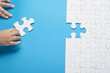 © Burhanuddin - Baby hand holding piece of white puzzle on blue background. Business and team work concept.