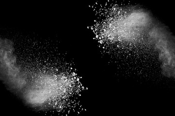 Freeze motion of white dust explosion on black background. Stopping the movement of white powder on dark background. Explosive powder white on black background.