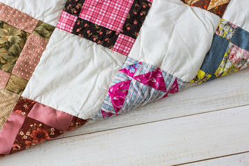 Wall Mural - homecraft, art, vintage concept. front view on a quilted blanket with square and triangle pattnern and colorfull print consist of roses, poppy and other types of plants