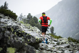 Fototapeta Góry - man running on high mountains  outdoor track in bad weather with fog and rain