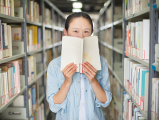 Portrait of a smiling young student reading a book in a library