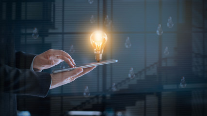 Poster - Glowing light bulb over labtop of businessman among the others that not bright, symbolic of creative and bright idea 