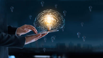 Glowing light bulb in brain over labtop of businessman among the others that not bright, it's symbolic of creative and bright idea or leadership, innovation and creativity concept