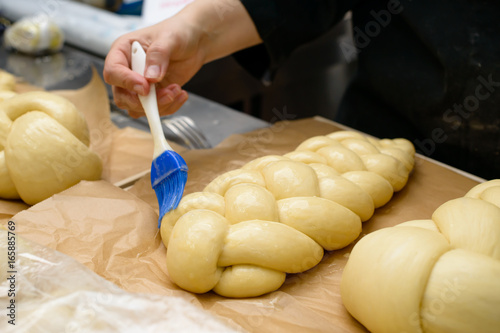 Fotografía female chef lubricate the bakery products with an egg yolk