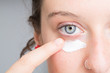 Woman applying a white cream on her face