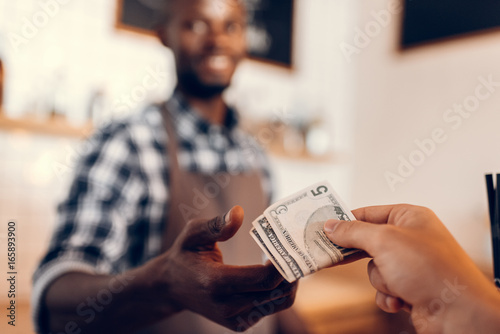 Fotografía selective focus of african american barista taking cash payment on bar counter i