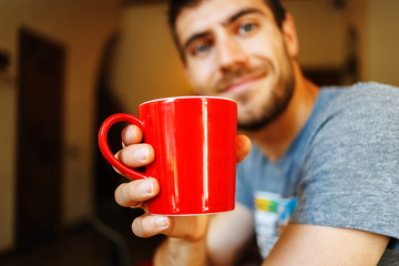 Red cup in the hands of a smiling Handsome