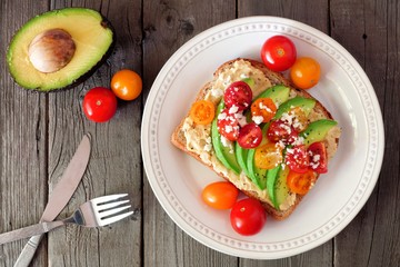 Sticker - avocado toast with hummus and tomatoes on plate, above scene on old wood background