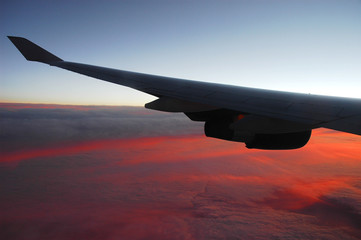 Wall Mural - red sunlight spreading on aerial cloud below airplane wing