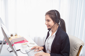 Young beautiful girl working at a laptop in a small medium enterprise. She is operating the phones and computer