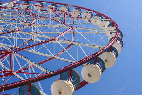 The Attraction Of A Ferris Wheel With Red And Blue Cabins In A