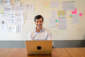 smile of Handsome business man sit on the chair and work with laptop at the office