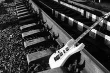 Black And White Electric Guitar On The Railroad Tracks And Stones