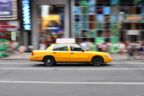 Fototapeta Koty - Panning shot of a taxicab at Times Square in New York, USA.