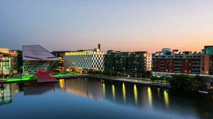 Wall Mural - Dublin, Ireland. Aerial view of Grand Canal docks in Dublin, Ireland at sunrise. Empty streets and illuminated modern buildings, colorful clear sky. Time-lapse from night to day