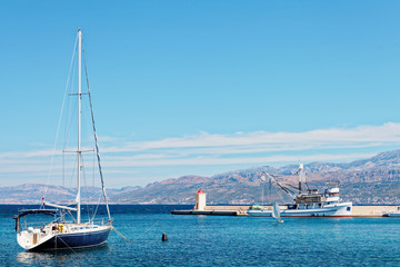 Wall Mural - Moored yatch and a fishing trawler in the harbor of a small town Postira - Croatia, island Brac