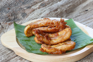 Fried banana fritters on banana leaf with wood plate