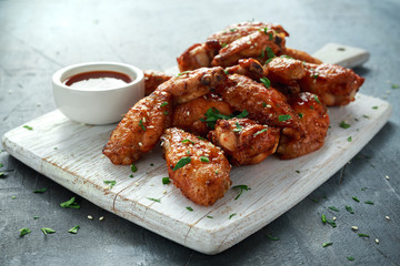 Wall Mural - Baked chicken wings with sesame seeds and sweet chili sauce on white wooden board.