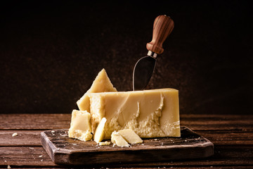 Wall Mural - Parmesan cheese on rustic wooden board. Pieces of cheese parmesan on wooden table with cheese knife.