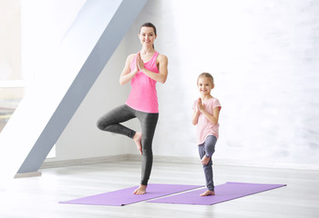 Wall Mural - Mother and daughter doing exercise indoors