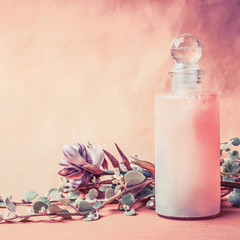 Wall Mural - natural cosmetic product in bottle with herbs and flowers on pink background, front view, square, co