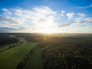 Wall Mural - 
Aerial view of a beautiful sunset over forest landscape with green fields