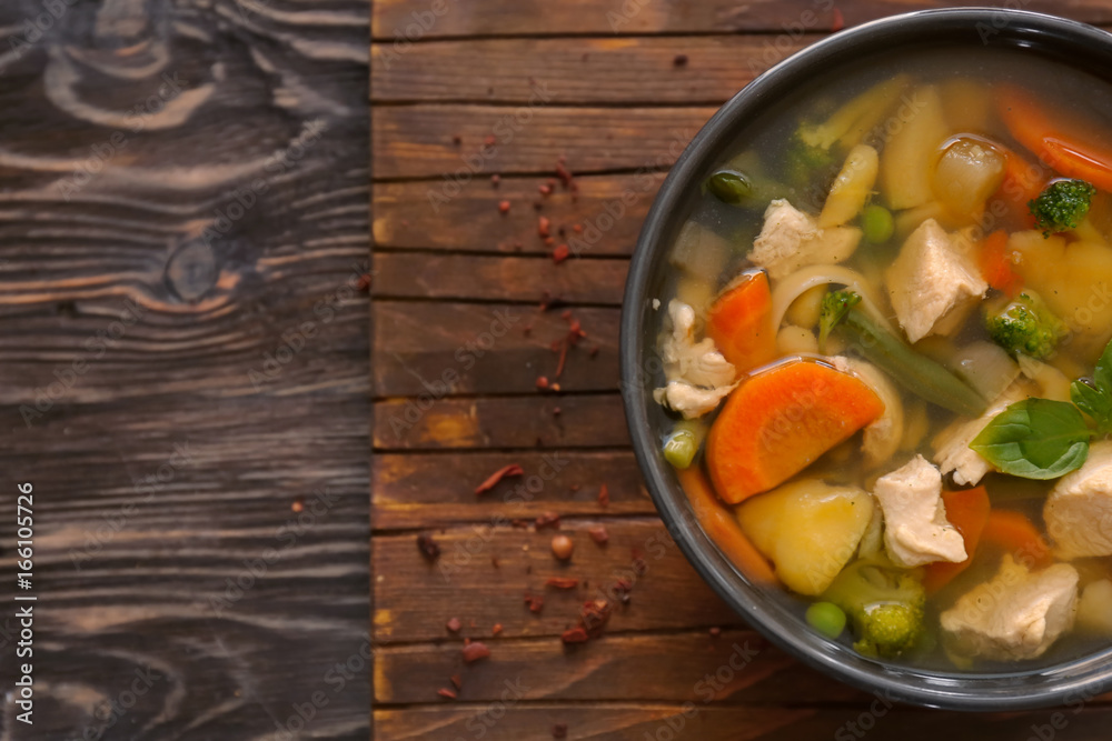 Bowl with delicious turkey soup on wooden board