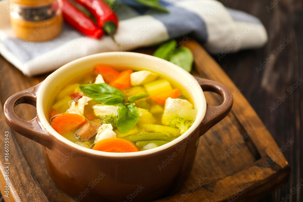 Casserole with delicious turkey soup on wooden board