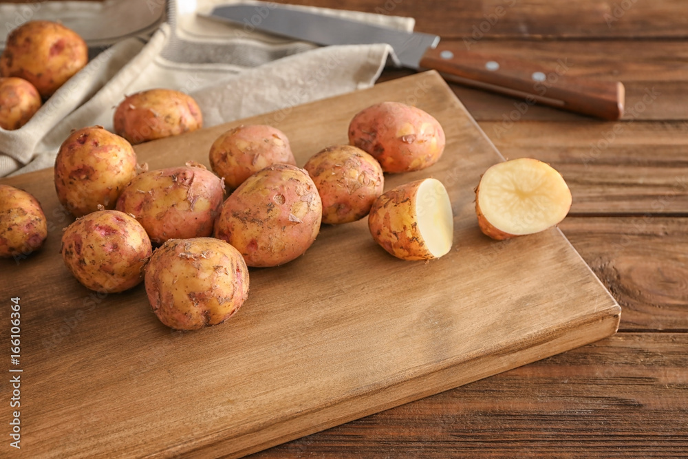 Raw organic potato on wooden board