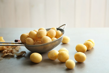 Strainer with raw organic potatoes on table