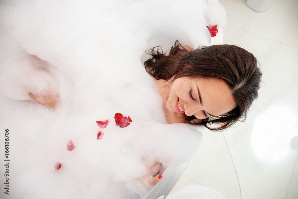 Beautiful woman relaxing in bathtub with foam
