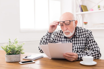 Wall Mural - Shocked senior man looking at bills copy space