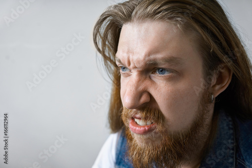 Close Up Studio Portrait Of Angry Mad Young Man With Thick Beard