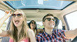 young friends fun inside car laughing happy singing in group and driving.