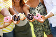 © Kalim - Group of friends eating donuts outdoors