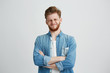 © Cookie Studio - Portrait of displeased young handsome man in jean shirt with crossed arms over white background.