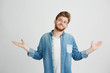 © Cookie Studio - Portrait of young handsome man smiling looking up shrugging over white background.